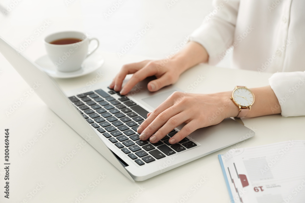 Young businesswoman using laptop at table in office, closeup - obrazy, fototapety, plakaty 