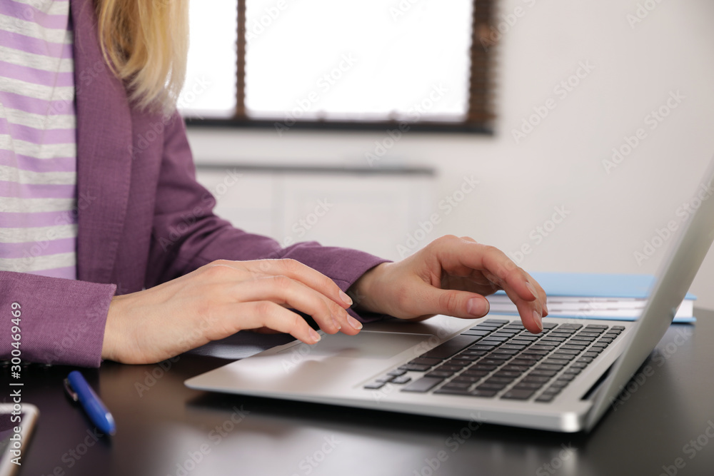 Young businesswoman using laptop at table in office, closeup Young businesswoman using laptop at table in office, closeup