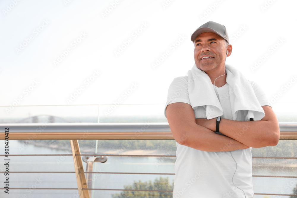 Handsome mature man in sportswear on bridge, space for text. Healthy lifestyle Handsome mature man in sportswear on bridge, space for text. Healthy lifestyle