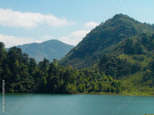 Lago azul con arboles verdes y montañas de fondo