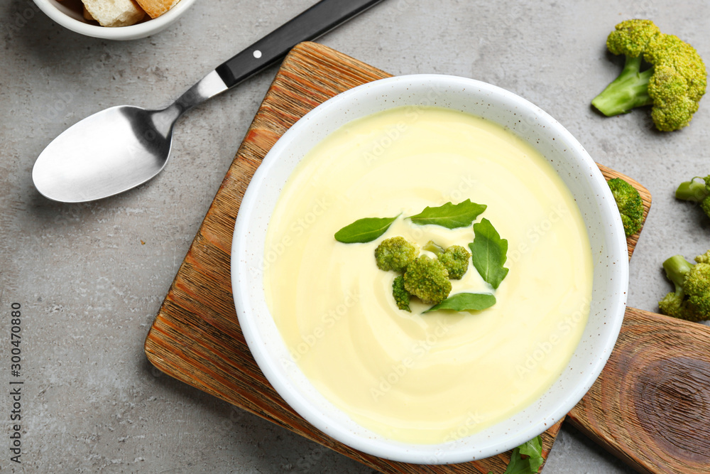 Flat lay composition with bowl of cheese cream soup and broccoli on grey table Flat lay composition with bowl of cheese cream soup and broccoli on grey table