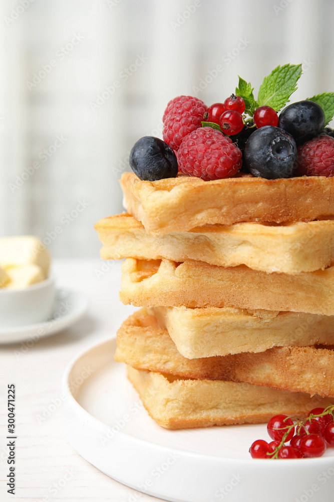 Delicious waffles with fresh berries served on white wooden table indoors Delicious waffles with fresh berries served on white wooden table indoors