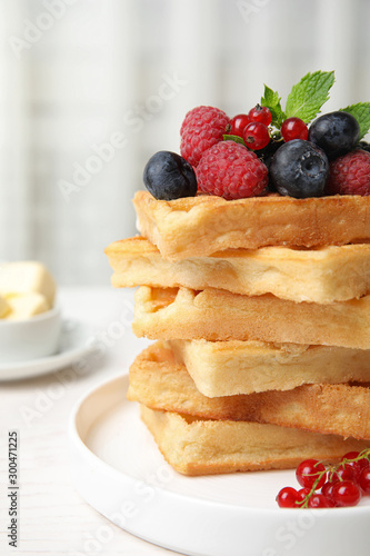 Delicious waffles with fresh berries served on white wooden table indoors