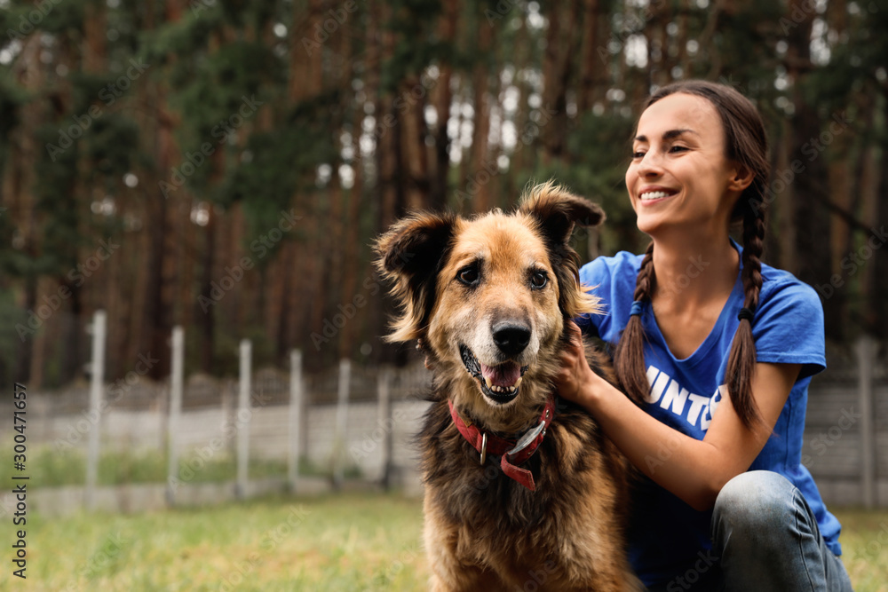 © New Africa - Female volunteer with homeless dog at animal shelter outdoors
