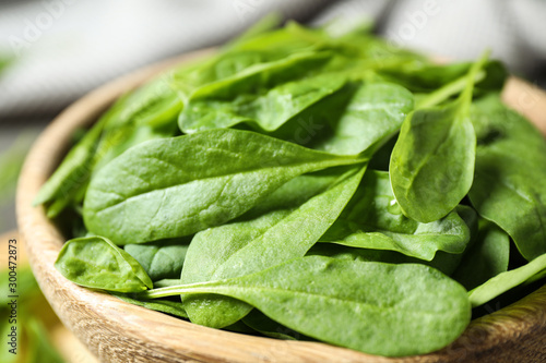 Fresh green healthy spinach in wooden bowl, closeup