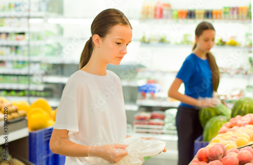 Teen girls shopping in supermarket reading product information. Choosing daily product.Concept of healthy food, bio, vegetarian, diet.