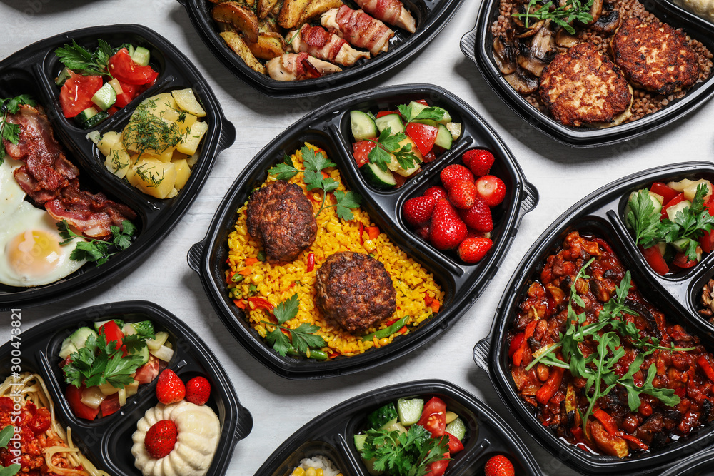 Lunchboxes with different meals on white table, flat lay. Healthy food delivery Lunchboxes with different meals on white table, flat lay. Healthy food delivery