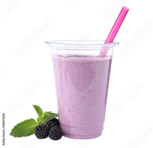 Tasty fresh milk shake in plastic cup and blackberries on white background