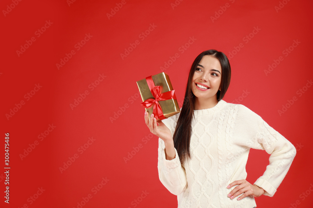 Happy young woman with Christmas gift on red background. Space for text Happy young woman with Christmas gift on red background. Space for text