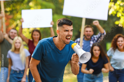 Canvas Print Angry young man with megaphone at protest outdoors