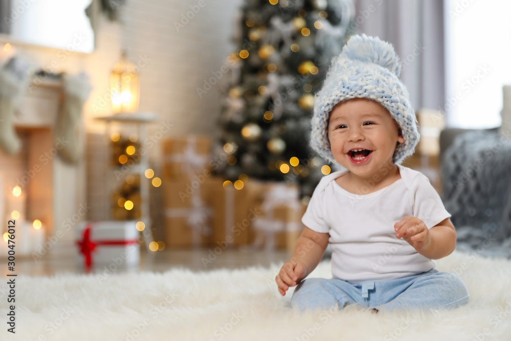 Little baby wearing knitted hat on floor at home. First Christmas - obrazy, fototapety, plakaty 