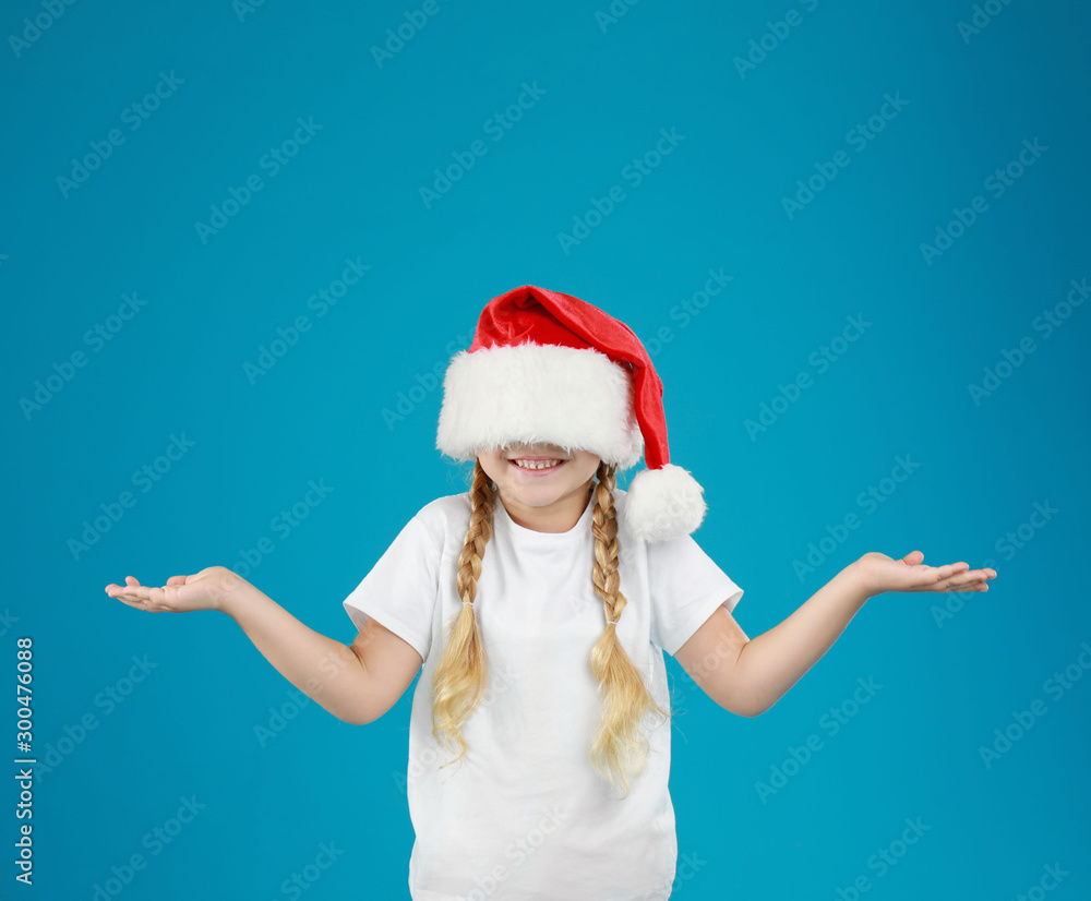 Cute little child wearing Santa hat on blue background. Christmas holiday Cute little child wearing Santa hat on blue background. Christmas holiday