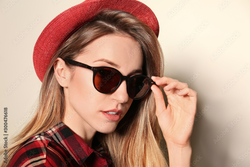 Young woman wearing stylish sunglasses on beige background Young woman wearing stylish sunglasses on beige background
