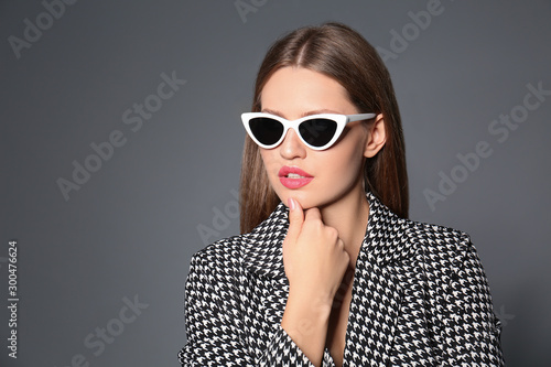 Young woman wearing stylish sunglasses on grey background. Space for text