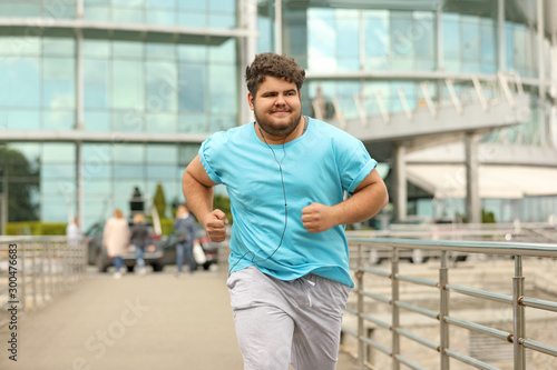 Young overweight man running outdoors. Fitness lifestyle
