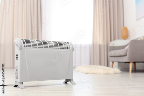 Modern electric heater on floor at home. Space for text photo