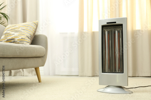 Modern electric infrared heater on floor at home. Space for text