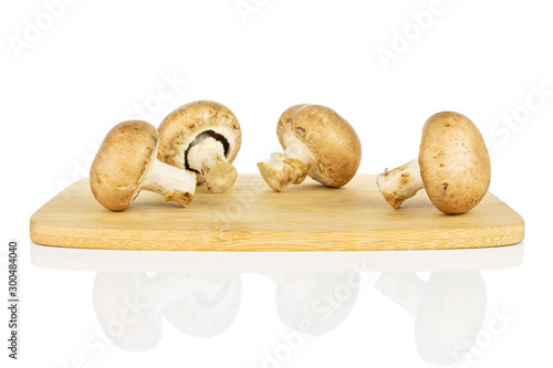 Group of four whole fresh brown champignon on bamboo cutting board isolated on white background