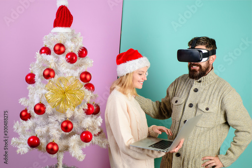 Virtual reality mask. New Year, Christmas, future and technology concept. Woman in santa hat with laptop. Bearded man in virtual 3D glasses at christmas. 3d technology, virtual reality, entertainment.