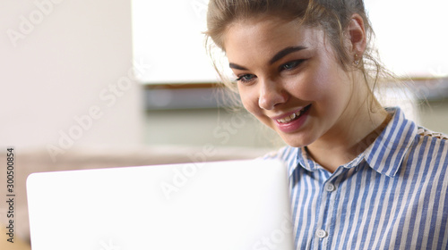 Happy brunette woman sitting on sofa with laptop photo