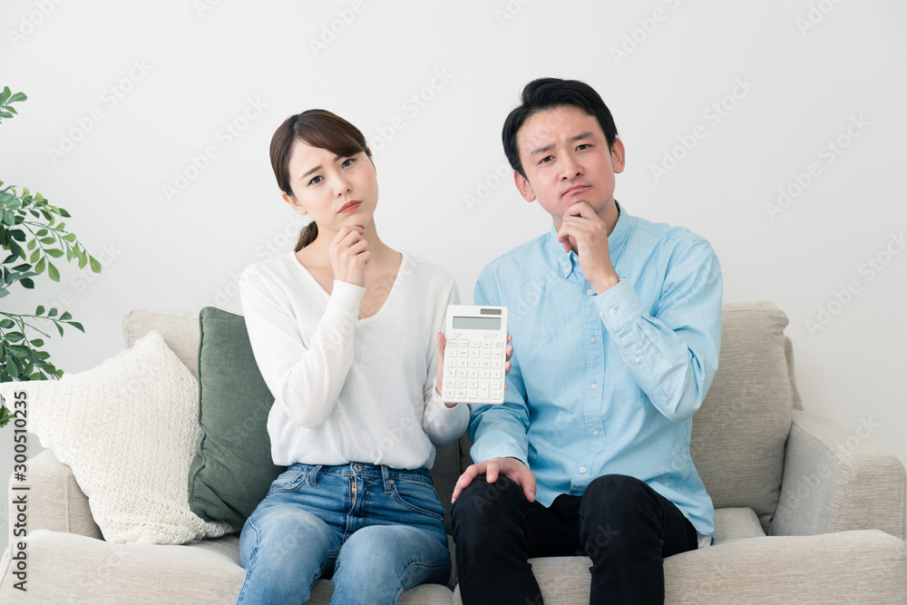 電卓を持って考える若い男女 電卓を持って考える若い男女