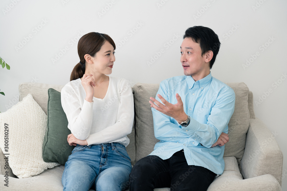 ソファーで話し合っている若い男女 ソファーで話し合っている若い男女