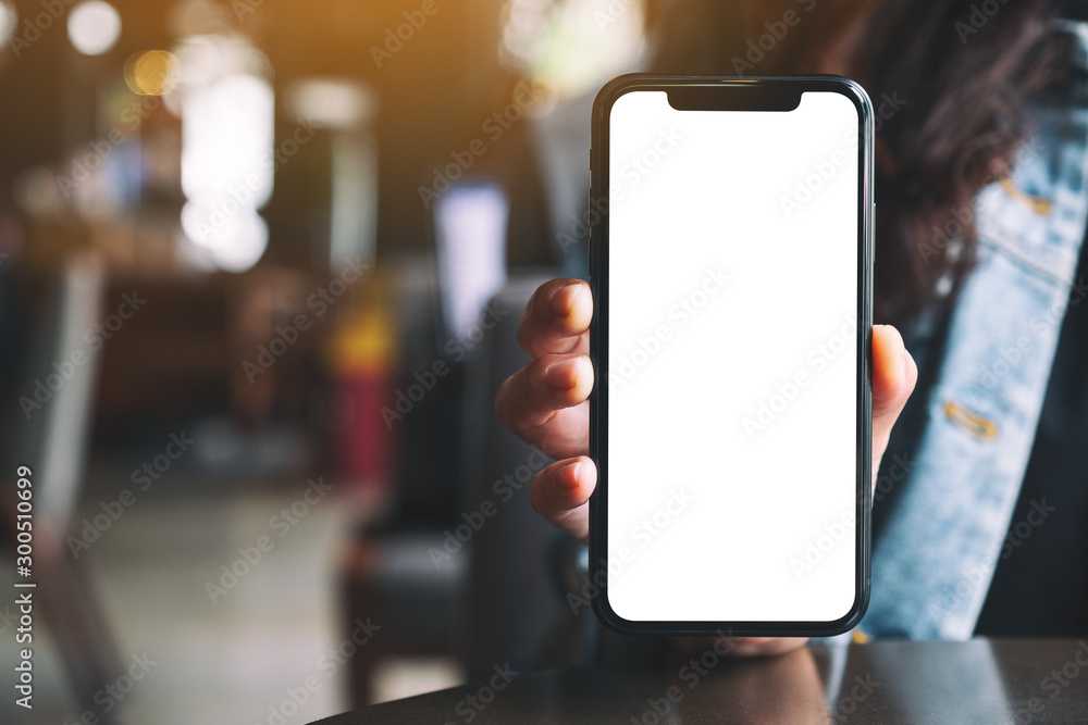 Mockup image of a woman holding and showing black mobile phone with blank screen in cafe Mockup image of a woman holding and showing black mobile phone with blank screen in cafe