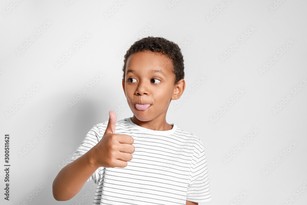 Grimacing African-American boy showing thumb-up gesture on white background Grimacing African-American boy showing thumb-up gesture on white background