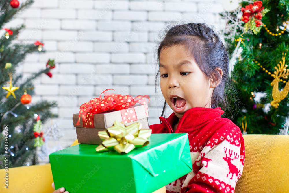 Cute asian child girl surprise with gift and holding beautiful gift boxes in hand on Christmas celebration