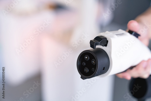hand holding plug for charging battery of an electric car