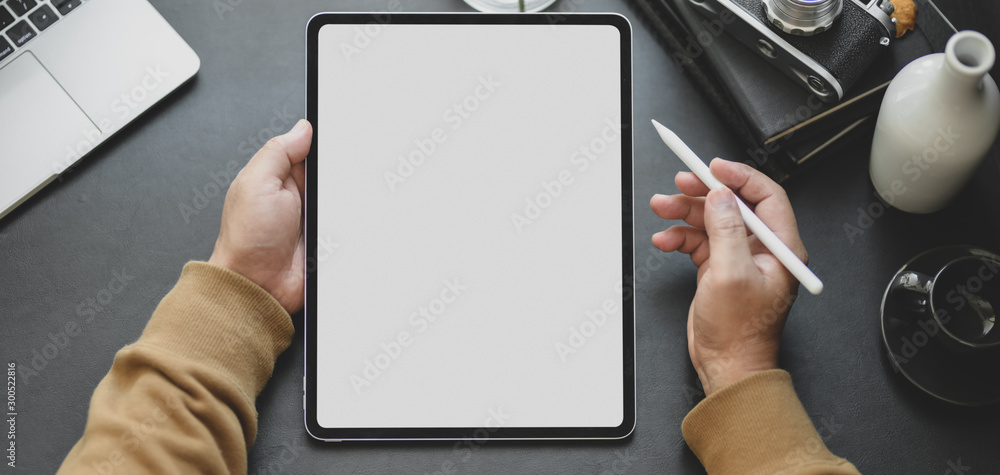 Close-up view of man using blank screen tablet while working in dark modern workplace - obrazy, fototapety, plakaty 