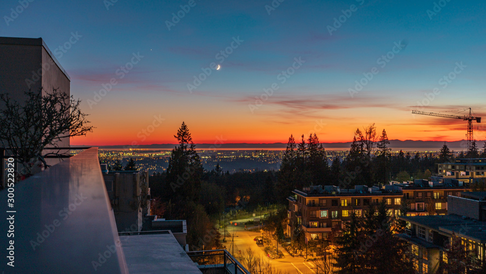 Naklejka premium Crescent Moon overlooking golden glow of sunset over Vancouver and the Gulf Islands in silhouette