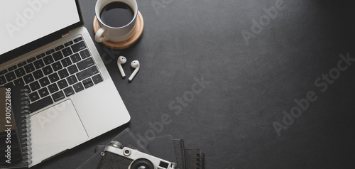 Close-up view of dark modern workplace with laptop computer and office supplies