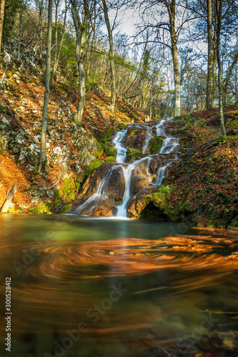 Brigth and warm colors and a beautiful stream and waterfalls in a wild mountain location in autumn