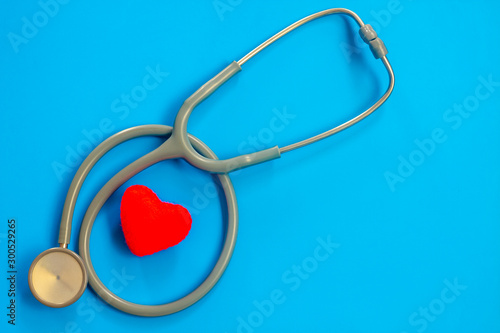 Stethoscope and red heart on a blue background with space for text.