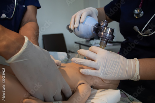 Neonatal reanimation medical instruccion ,yong doctors with a baby mannequin or model. Face mask, pulmonary ventilation and heart massage. Team work concept. Neonatology. 