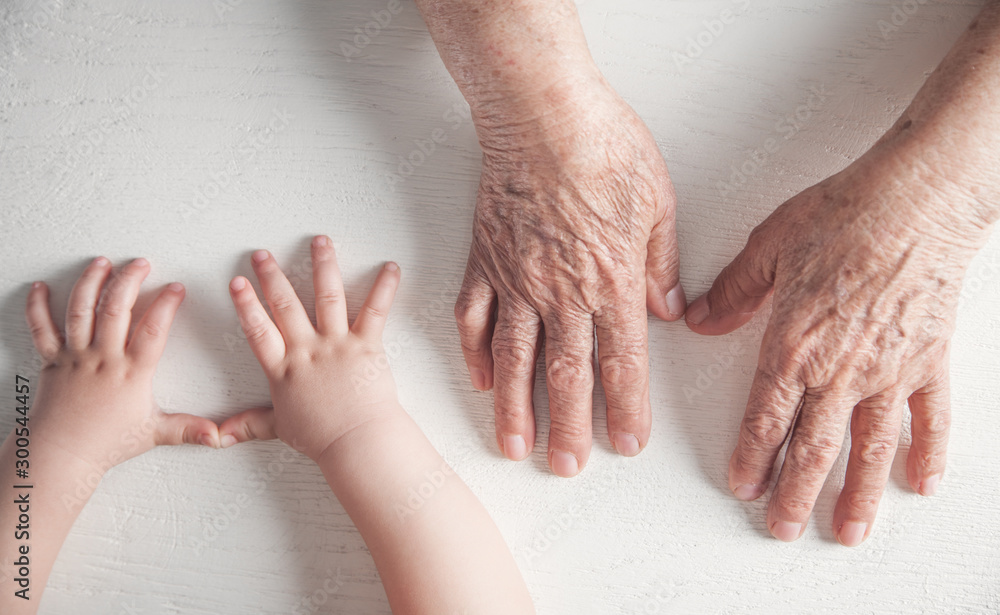 Elderly woman and a kid hands together. - obrazy, fototapety, plakaty 