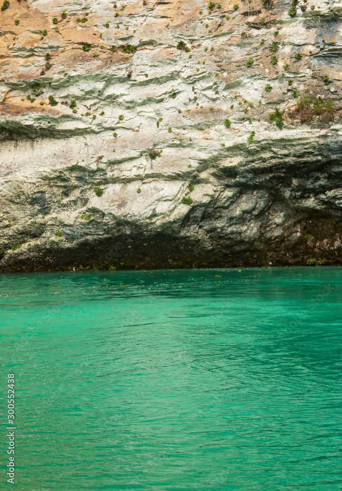 cliff above the river with green water