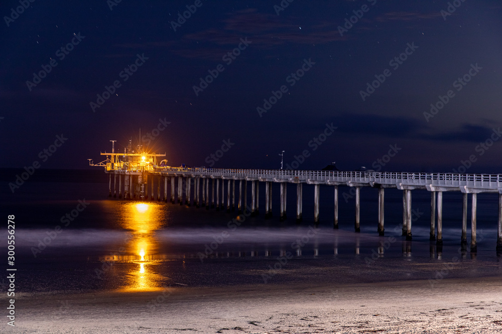 Fototapeta premium A long pier stretching into the ocean at nigh. Long exposure shot.