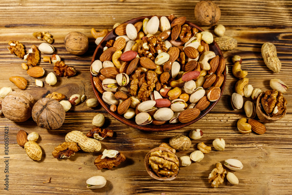 Mixed nuts on wooden table. Walnuts, pistachio, almond, peanut, cashew, hazelnut in ceramic bowl. Healthy eating concept Mixed nuts on wooden table. Walnuts, pistachio, almond, peanut, cashew, hazelnut in ceramic bowl. Healthy eating concept