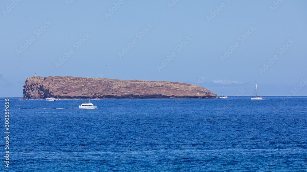 Panoramic view at Molokini Island from Big Beach, Maui, Hawaii. Cruise boats sail along.