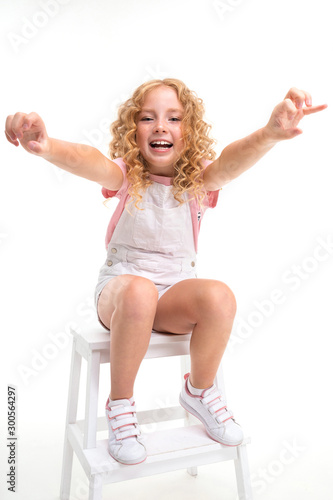 Happy cild with fair red curly hair sits on a chair and smile isolated on white background photo