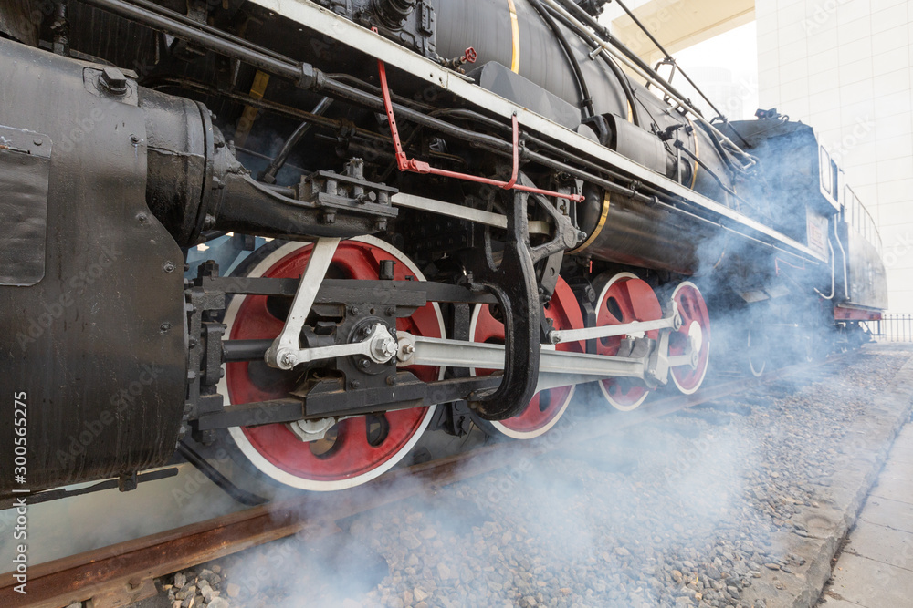 Naklejka premium Close-up of a driving wheel of an old-fashioned steamed red-black painted vintage steam train