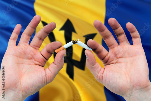 Barbados quit smoking cigarettes concept. Adult man hands breaking cigarette. National health theme and country flag background.
