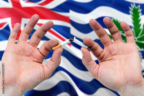 British Indian Ocean Territory quit smoking cigarettes concept. Adult man hands breaking cigarette. National health theme and country flag background.