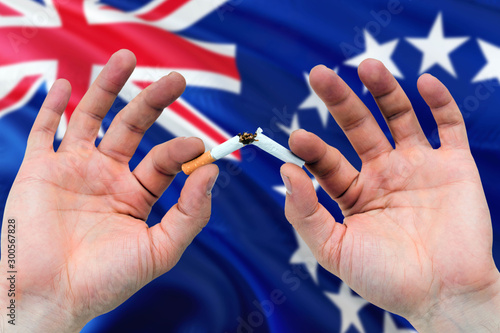 Cook Islands quit smoking cigarettes concept. Adult man hands breaking cigarette. National health theme and country flag background.
