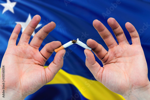 Curacao quit smoking cigarettes concept. Adult man hands breaking cigarette. National health theme and country flag background.