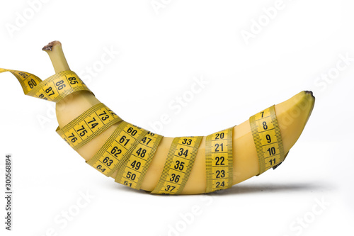 A measuring tape wrapped around a banana. The concept of penis enlargement, healthy eating, dieting and weight loss