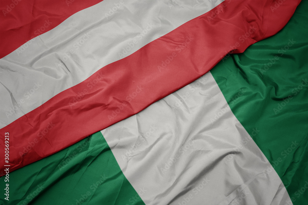 waving colorful flag of nigeria and national flag of austria.