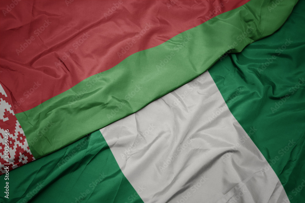 Obraz premium waving colorful flag of nigeria and national flag of belarus.
